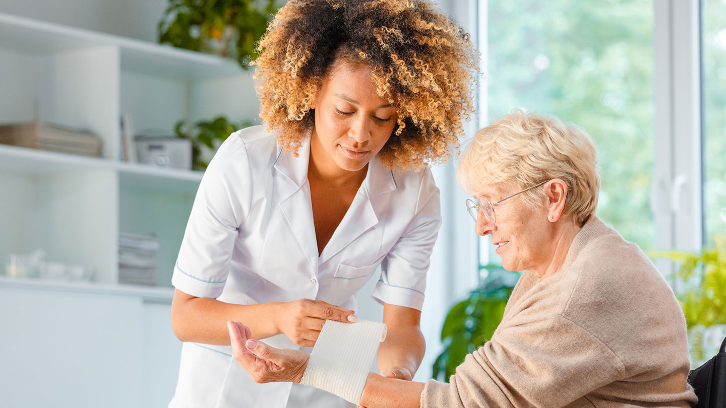 elderly person falls - caregiver helping elderly woman wrap a bandage around her wrist from minor injury