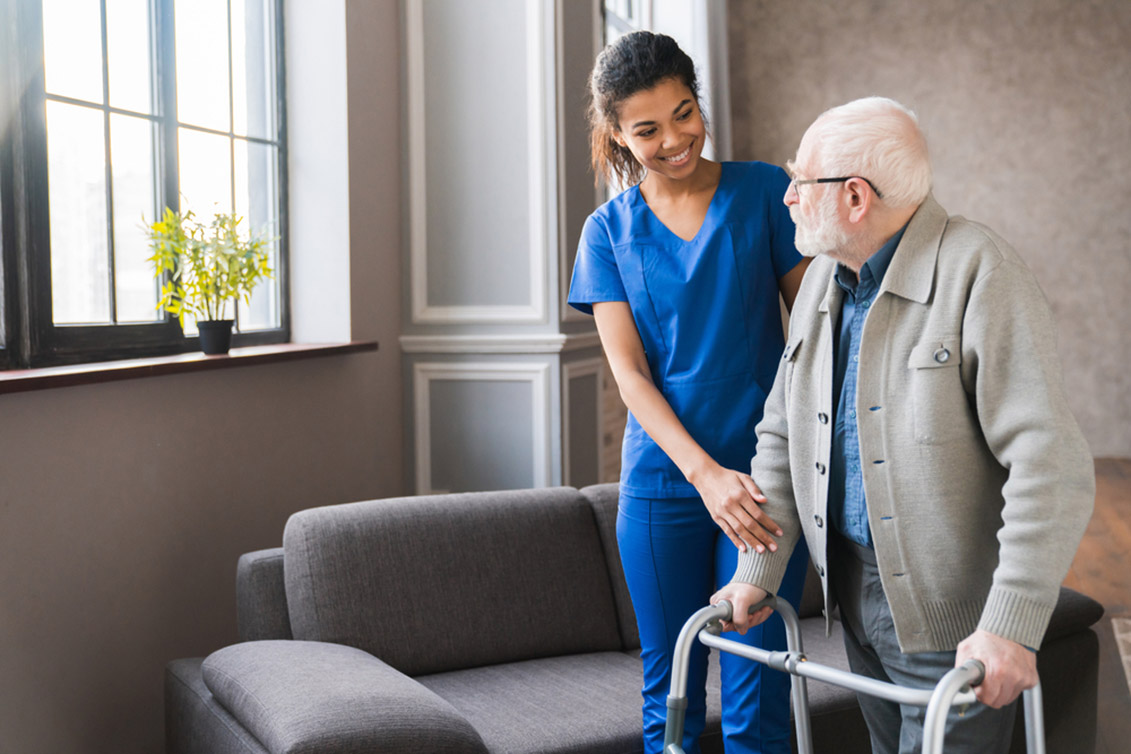 elderly person falls - female caregiver guiding an elderly man with his walker