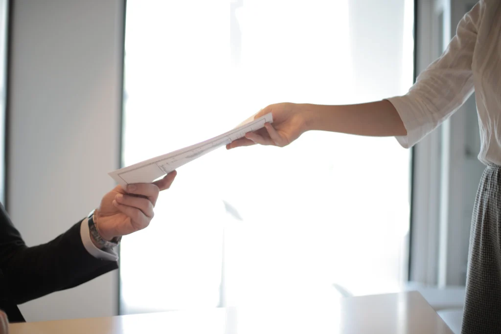 Woman handing a resume to a man sitting at a desk