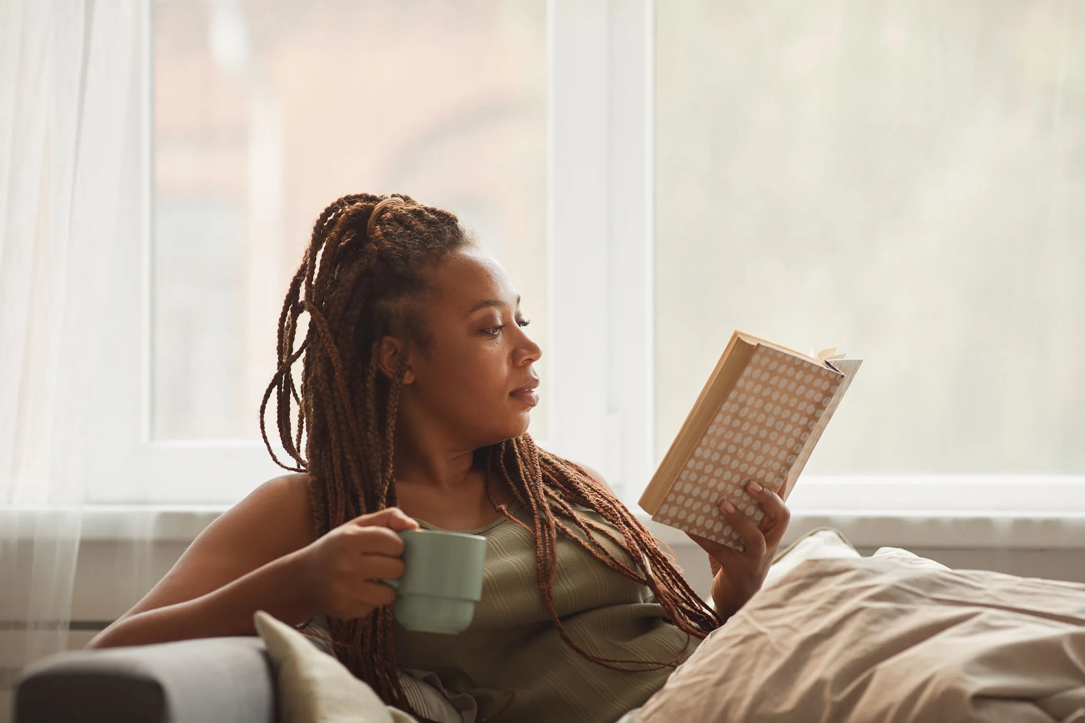 woman reading book and drinking coffee