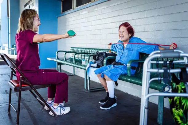 nurse and elderly woman doing physical therapy for post surgery care