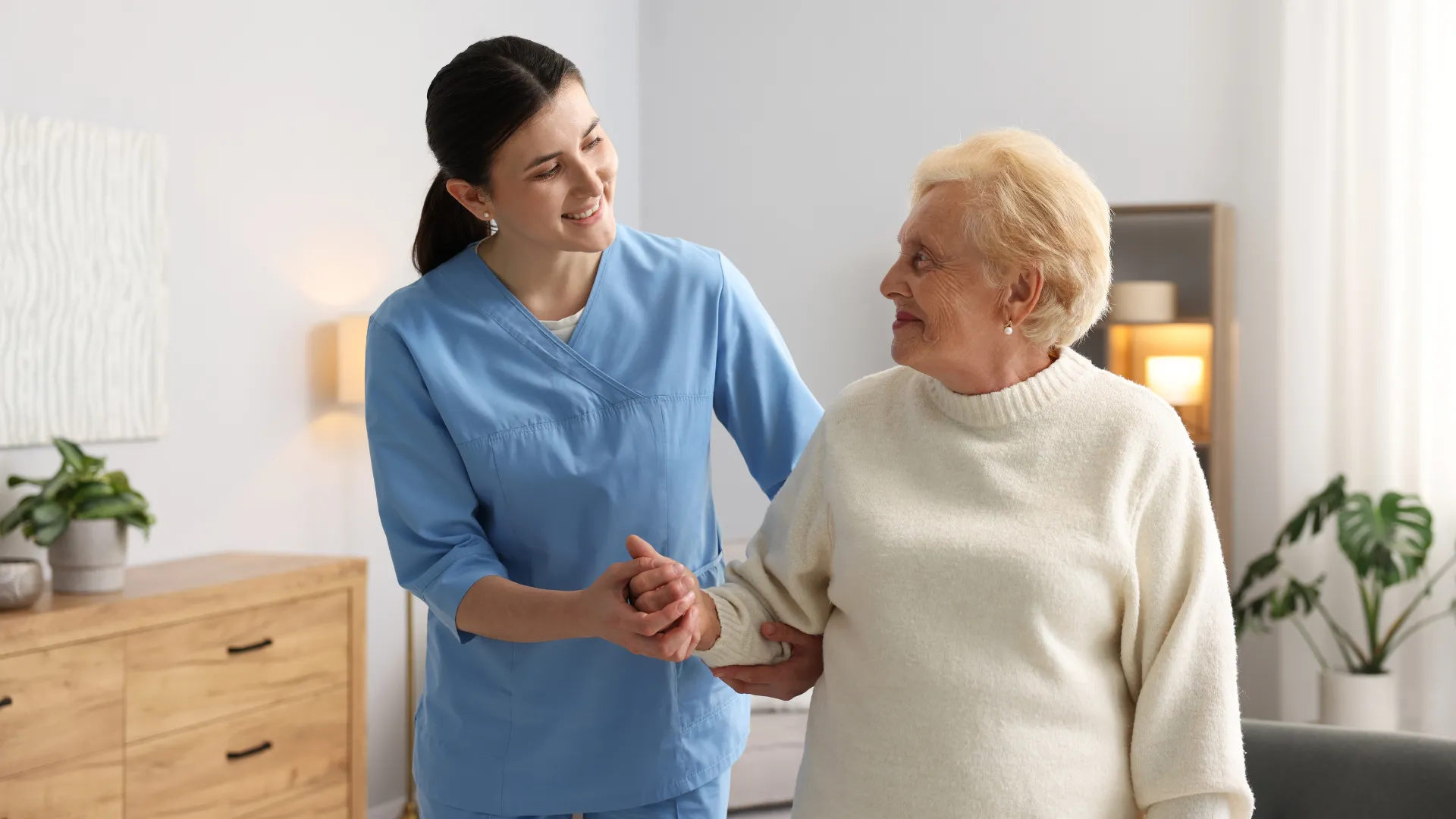 Caregiver assisting elderly woman indoors